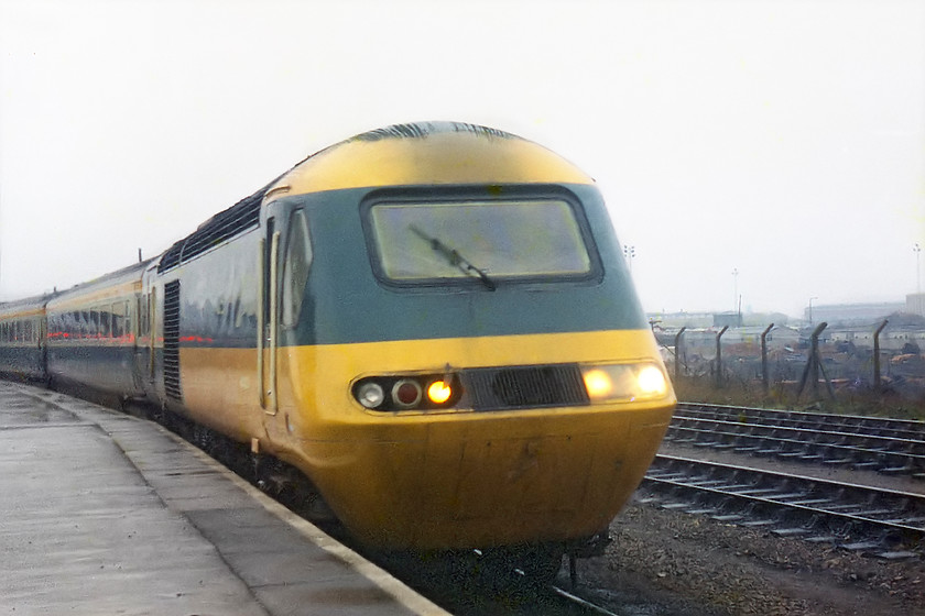 Class 43, unidentified up working , Swindon station 
 A class 43 HST arrives at Swindon station on a gloomy day. The running lights glowing in the poor light only emphasises what a dull day this was! Notice that this HST has one of its plastic light covers missing, a common affliction at this time. 
 Keywords: Class 43 HST Swindon