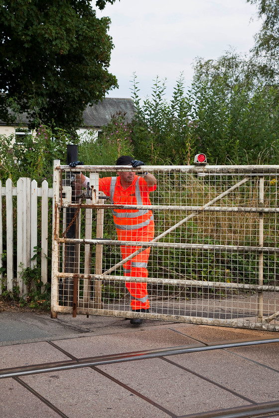 Closing the crossing gates, Burneside SD503954 
 The signalman has emerged from his keeper's hut and is closing the gates to road users in the village of Burneside. Despite it being a fairly quiet village a fair number of vehicles soon built up either side of the gates. 
 Keywords: Closing the crossing gates Burneside SD503954