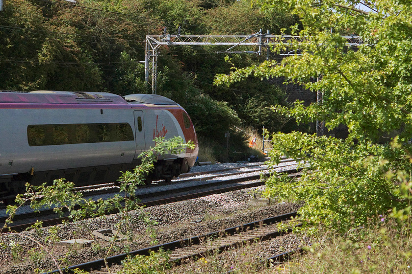 390011, VT 13.00 London Euston-Manchester Piccadilly (1H26), passing the TSR, Ashton Road bridge 
 390011 'City of Lichfield' passes, at walking pace, over a TSR just south of Roade forming the Virgin Trains' 13.00 Euston to Manchester Piccadilly. Just noticeable, sitting on the afternoon sun, trackside is an observer who was checking the passage of all trains over the freshly repaired section of track and the fresh ballast that was yet to be tamped to a proper finish. 
 Keywords: 390011 13.00 London Euston-Manchester Piccadilly 1H26 passing the TSR, Ashton Road bridge