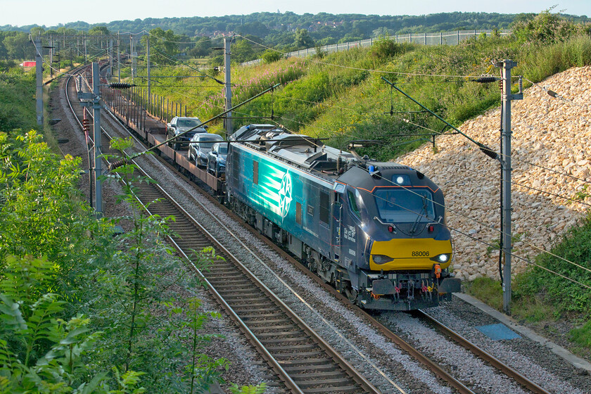 88006, 16.49 Garston-Dagenham (6L48, 9E), Milton Malsor SP738560 
 I had selected this location to capture the passage of the returning charter that was due to pass this spot in about half an hour's time. However, as one can see I misjudged the position of the setting sun with almost all of this train now in the shade; an urgent plan B was needed! 88006 hauls the empty 16.49 Garston to Dagenham car transporters past Milton Malsor just south of Northampton. Once again there are just three solitary vehicles on this train rather like when I saw it last time, see.... https://www.ontheupfast.com/p/21936chg/30015904775/x88006-15-49-garston-dagenham-6l48 and I still none the wiser as to why this is? Notice the red lorry in the top left corner of the photograph heading north on the nearby M1. 
 Keywords: 88006, 16.49 Garston-Dagenham (6L48, 9E), Milton Malsor SP738560