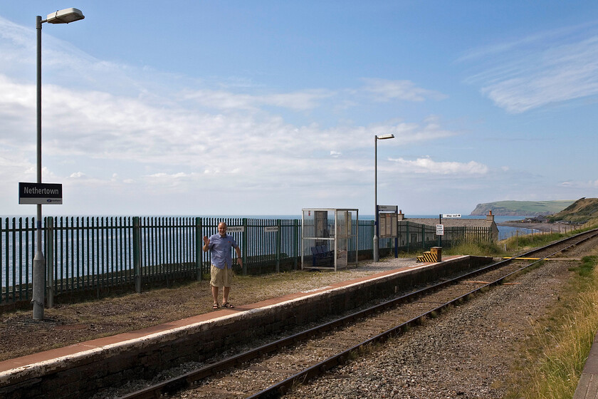 Andy, Nethertown station 
 This mast rank as one of the remotest stations on the network? It is accessed down a very narrow, steep and partially unmade road that seems to drop off the cliff edge as you begin the descent! The station used to be a lot busier serving a nearby wartime training camp but, as can be seen now, it is a single-track affair that has a very meagre stopping service. Andy enjoys copping this station and gives me a cheery wave with the Irish Sea in the background. The promontory to the right is the bulk of St. Bees Head.

NB I attempted to replicate this image in our summer 2024 visit to the station, see.... https://www.ontheupfast.com/p/21936chg/30056636811/andy-nethertown-station 
 Keywords: Andy Nethertown station