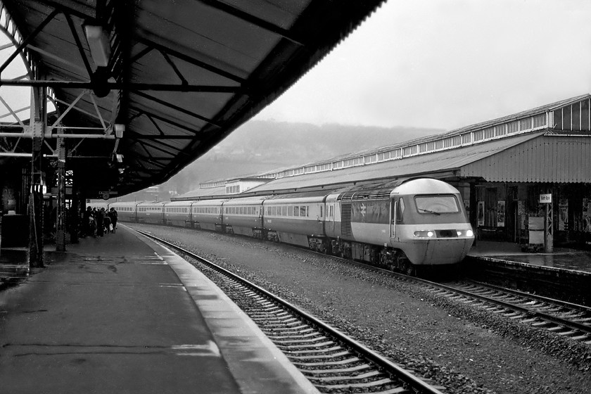 Class 43, unidentified down working, Bath Spa station 
 With the Western Region struggling to keep its HSTs together as numbered sets they gave up the use of a 253 designation on the nose of the power cars. This forced spotters to identify the individual power cars numbered in the series W430XX. As it transpired these were the identifiers that remained until the powers cars were withdrawn from service in 2109 albeit minus the 'W' or 'E'. Unfortunately, I have recorded neither numbers here at a very wet Bath Spa as an unidentified set arrives with a down service from Paddington. In more recent years, the scene has changed very little, see..... https://www.ontheupfast.com/p/21936chg/30013687912/x6-166204-gw-13-23-portsmouth-h-cardiff 
 Keywords: Class 43 HST down working Bath Spa station