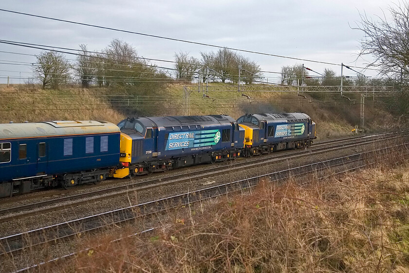 37611 & 37259 (failed), outward leg of The Enigmatic Logistition, 08.21 Crewe-Wolverton (1Z34, 2L), Roade Hill 
 A pair of DRS' finest lead the outward leg of The Enigmatic Logistition charter south on the WCML between Roade and Ashton. Running as 1Z34 the charter left Crewe at 08.21 but had its planned itinerary severely modified due to the failure of 37259 seen second in this photograph leaving 37611 to do the work at the front. I am not so sure that the hapless chartergoers on board would have been too happy to have lost what was effectively half of their planned route. 
 Keywords: 37611 37259 failed The Enigmatic Logistition 08.21 Crewe-Wolverton 1Z34 Roade Hill DRS Direct Rail Services