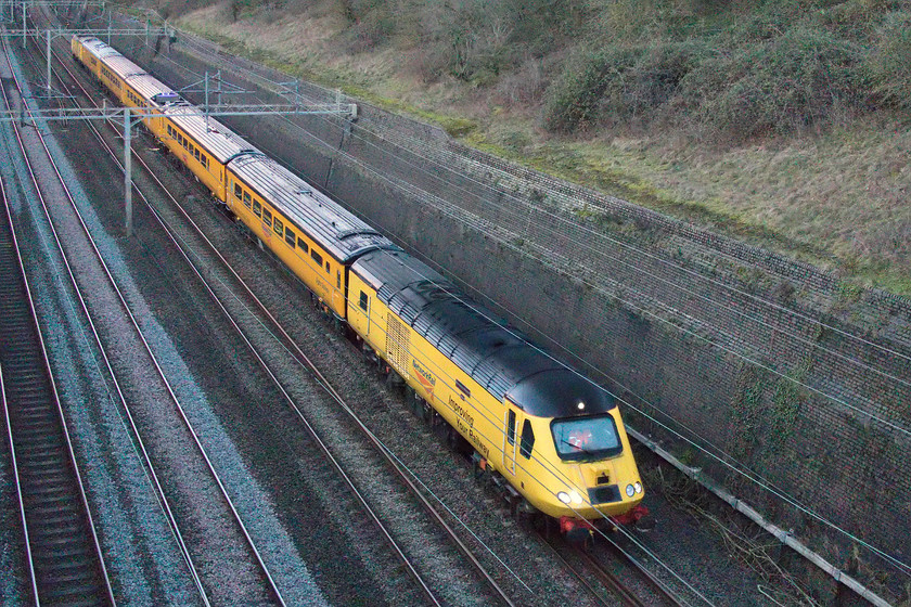 43013 & 43014, NR 14.24 Derby RTC-Derby RTC (1Q28, 36E), Roade cutting 
 At 16.32 during the last week of January every minute meant it was getting significantly darker! I was thwarted a little by a delayed London Northwestern service that control let out in front of the NMT at Northampton. This meant that the light in the cutting was absolutely dire so I had to ramp the camera's ISO up to 20000. I had to do a fair amount of Photoshop processing in order to get a half-decent image of the New Measurement Train working its weekly 1Q28 14.24 Derby RTC return working that heads to Euston then back again to Derby via Crewe. It is interesting that this is one of the few trains that traverse the short section of line from Wichnor Junction to Lichfield Trent Valley low level utilising the short single track chord from Lichfield Trent Valley Junction. The NMT is being worked by 43013 'The Railway Observer' and 43014 'Mark Carne CBE' two power cars that have been a pair since their introduction in 1976 as set 253007 that I photographed back in 1980, see..... https://www.ontheupfast.com/p/21936chg/29751821804/x253007-14-25-london-paddington-penzance Notice the large ultraviolet camera on the roof of the third coach that was imaging the registration arm of every catenary mast with a burst of purple light every time it passed under one, illuminating the cutting in a vaguely psychedelic way! 
 Keywords: 43013 43014 14.24 Derby RTC-Derby RTC 1Q28 Roade cutting via Euston Crewe New Measurement Train NMT flying banana 43013 'The Railway Observer' and 43014 'Mark Carne CBE'