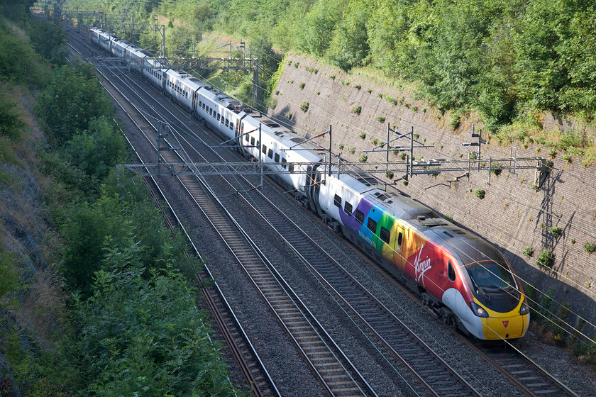 390055, VT 08.05 London Euston-Glasgow Central (1S42, 15L), Roade Cutting 
 Virgin Train unveiled this livery on 390055 on May 16th 2018. It is vinyl wrapped in the rainbow livery and tagged with #RideWithPride. This to celebrate Virgin's association with all the Pride events during the summer of 2018. This particular Pendolino also was subject to another seasonal livery, the #Pengulino one of December 2015. The train is seen passing through Roade Cutting forming the 08.05 London Euston to Glasgow, unfortunately, this 1S42 arrived some 15 minutes late into Central station. 
 Keywords: 390055 1S42, Roade Cutting