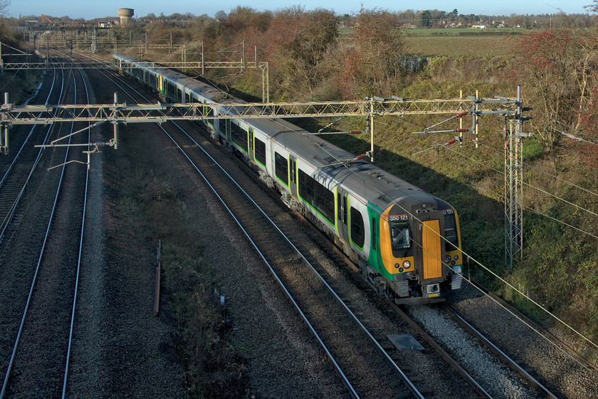 350121 & 350265, LN 12.14 Birmingham New Street-London Euston (1Y22, 2E), Victoria bridge 
 Despite it being only just after lunch, the low cutting at Victoria bridge near Roade is nearly in complete shade so low is the sun just a month away from the shortest day. 350121 and 350265 pass working the 12.14 Birmingham New Street to London Euston. 
 Keywords: 350121 350265 12.14 Birmingham New Street-London Euston 1Y22 Victoria bridge