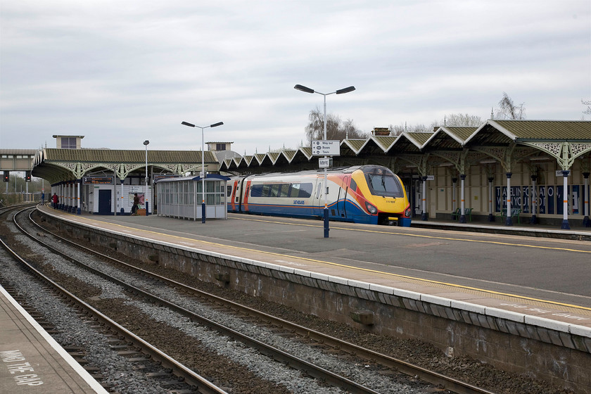 222022, EM 10.05 Nottingham-London St. Pancras (1B31), Kettering station 
 A photograph that shows the station constructed during 1857 to the designs of C H Driver. The design is classic Midland Railway with ridge-and-furrow canopies, which span two flat-roofed, single-storey weather-boarded buildings on platforms two and three. These canopies are slightly later added during expansion between 1877 and 1879. The station is Grade II listed by Historic England who are going to have to be on top of their game if the plans to electrify the line come to fruition. 222022 'Invest In Nottingham' heads south working the 1B31 10.05 Nottingham to St. Pancras service. 
 Keywords: 222022 10.05 Nottingham-London St. Pancras 1B31 Kettering station East Midlands Trains Meridian Invest In Nottingham