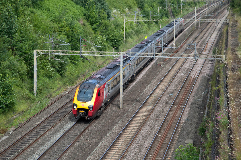 Class 221, VT 09.50 Birmingham New Street-London Euston (1B12, 17L), Roade Cutting 
 Identifying class 221 Voyagers from this lofty position is impossible. The only way is if it's a named example and even then if the nameplate can be snapped as the train passes. Here, the heavily delayed 09.50 form Birmingham New Street to London Euston passes through Roade Cutting. It had been caught behind a number of trains that that were running on caution following the passage of a 70mph Freightliner along the up fast. This was because the Northampton line was closed northwards towards Rugby. 
 Keywords: Class 221 1B12 Roade Cutting