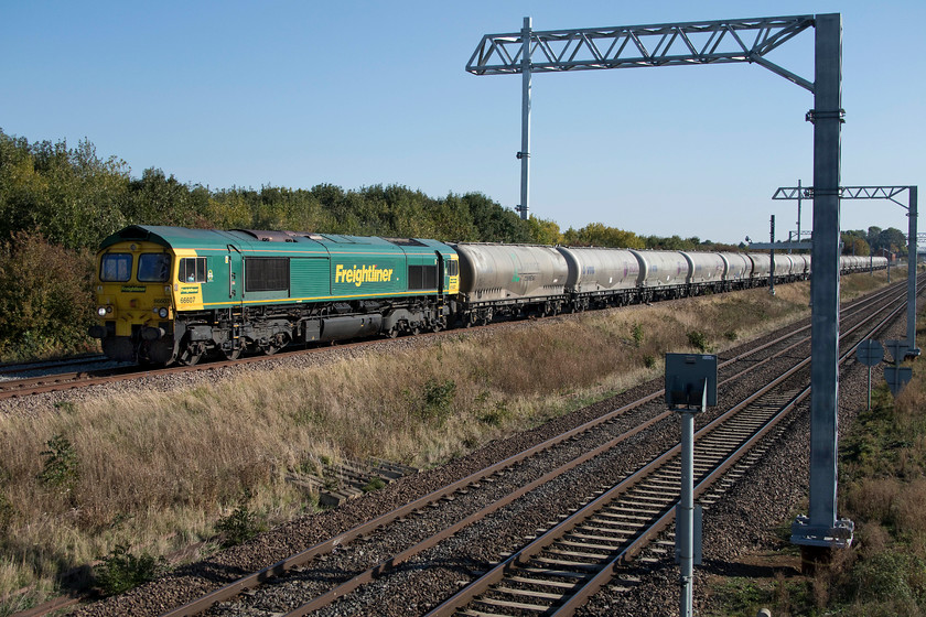 66607, 11.13 Theale Lafarge-Hope Earles Sidings (6M91), Irchester SP927667 
 66607 brings the daily 11.13 Theale to Hope Sidings 6M91 empty cement train down the slow line at Irchester just south of Wellingborough. The newly installed electrification masts now are a feature of this previously open view but will soon become a much more dominant one as the masts are installed on the up and down slow. 
 Keywords: 66607 11.13 Theale Lafarge-Hope Earles Sidings 6M9 Irchester SP927667