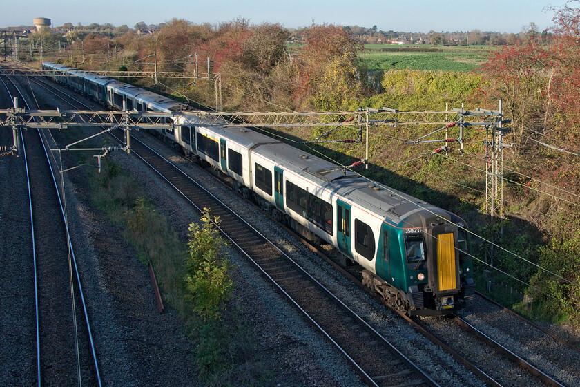 350231 & 350114, LN 14.05 Northampton-London Euston (2N10, 2L), Victoria bridge 
 Despite it being early November the sun is out and it is extraordinarily mild to the extent that I was able to walk out from home in shorts! Indeed, the following day (Sunday 13th November) saw the warmest day at 21.5 degrees celsius recorded in North Wales at the latest point in any year. 350231 and 350114 pass Victoria bridge near Roade (seen in the background) working the 14.05 Northampton to Euston service. 
 Keywords: 350231 350114 14.05 Northampton-London Euston 2N10 Victoria bridge London Northwestern Desiro