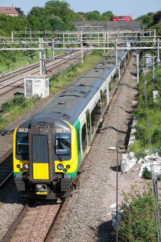 350377 & 350108, LM 09.25 Northampton-London Euston (1W70), site of Roade station 
 Having completed its school run contracts, a Country Lion double-deceker bus crosses the A508 road bridge in Roade. Meanwhile, 350377 and 350108 pass with the 09.25 Northampton to Euston working. The spot where the train is passing was where the platforms of Roade's long closed railway station was located. 
 Keywords: 350377 350108 09.25 Northampton-London Euston 1W70 site of Roade station