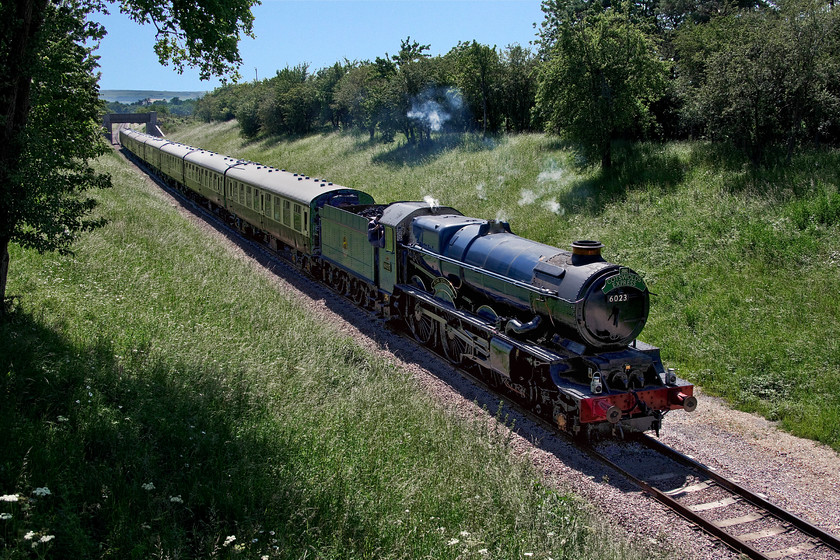 6023, 13.55 Cheltenham Racecourse-Broadway, Stanton SP059343 
 Oh, the perils of high summer photography! As the northern extension of the Gloucestershire and Warwickshire Railway runs north to south getting a northbound train that is not backlit for a large part of a summer's day is all but impossible. In addition, the warmth of summer also means no exhaust from a steam train but for a whisper emerging from the chimney of 6023 'King Edward II'. A bit of playing within Photoshop has enabled this picture to be presented of the 13.55 Cheltenham Racecourse to Broadway. I am standing a narrow footpath bridge that sits atop a brand new aqueduct that carries a tiny watercourse over the railway. 
 Keywords: 6023 13.55 Cheltenham Racecourse-Broadway Stanton SP059343