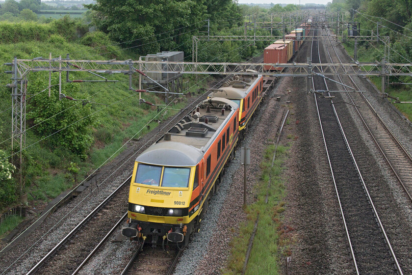 90012 & 90007, 02.50 Felixstowe North-Garston (4M45, 54E), Victoria bridge 
 Despite Class 90s being relatively short locomotives, a pair does not quite fit properly within the framing of the overhead gantry at Victoria bridge just south of Roade. Genesee & Wyoming liveried 90012 and 90007 lead the 4M45 02.50 Felixstowe to Garston Freighliner service. Despite leaving the Felixstowe North terminal before the previous down freight service this one runs second to it following a lengthy stopover in Wembley Yard. 
 Keywords: 90012 90007 02.50 Felixstowe North-Garston 4M45 Victoria bridge Genesee & Wyoming Freightliner