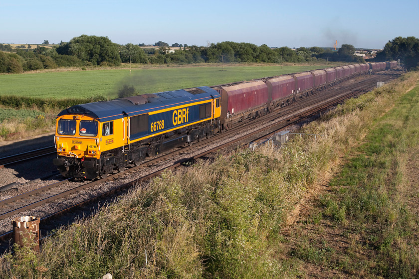 66788, 18.49 Wellingborough-Peak Forest (4Z86), Harrowden Junction 
 Looking very smart in its GBRF livery, 66788 makes a smokey departure from the down slow to the fast at Harrowden Junction. It was hauling the 18.49 Wellingborough Yard to Peak Forest empty stone wagons running as 4Z86. This image has a potent of things to come! Notice the piling that has been installed in the foreground to the bottom left of the image. This had only been placed the previous night and will soon be added to as the electrification mast is installed into it, totally spoiling this unfettered view. 
 Keywords: 66788 18.49 Wellingborough-Peak Forest 4Z86 Harrowden Junction