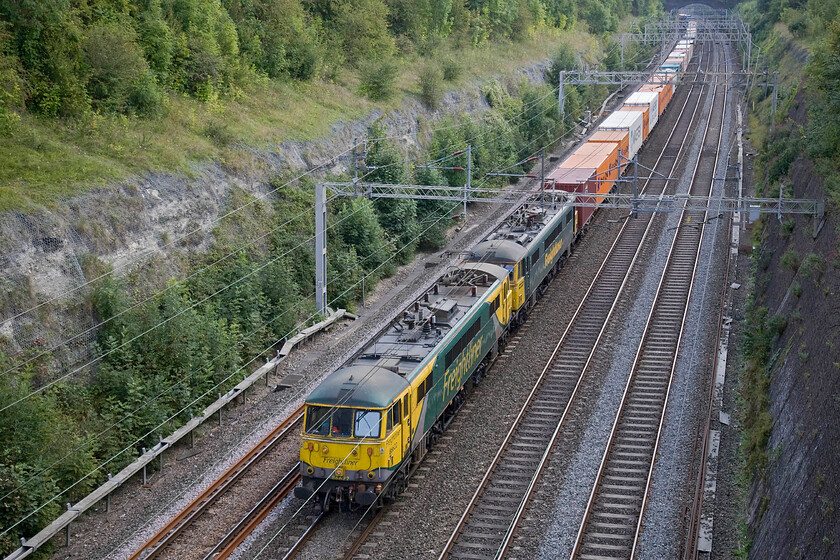 86622 & 86632, 10.10 Tilbury-Crewe Basford Hall (4M54), Roade cutting 
 Classic traction passes through Roade cutting in the form of veteran AC1s 86622 and 86632. They are working the 4M54 10.10 Tilbury to Crewe Basford Hall Freightliner service. After entering service on the WCML in the summer of 1965 as E3174 the leading locomotive went through a number of identities. From TOPS on 01.01.73 it became 86022, then from May 1980 it was 86322, from November 1985 it changed again to become 86422 and finally into this, probably its final number in the spring of 1990. 86632 is a year younger dating from 1966 and went through the same pattern of number changes throughout its life. 
 Keywords: 86622 86632 10.10 Tilbury-Crewe Basford Hall 4M54 Roade cutting