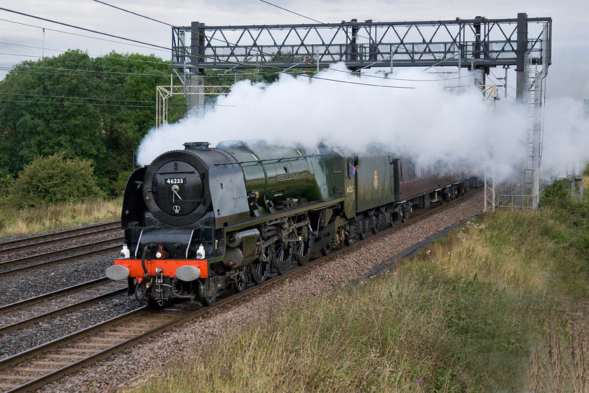 46233, outward leg of The Cathedrals Express, 07.16 Rugby-Bristol Temple Meads (1Z62, 34L), Roade hill 
 46233 'Duchess of Sutherland' looks completely at home on the WCML in its authentic Brunswick green livery as it hauls the outward leg of The Cathedrals Express charter that left Rugby at 07.16. The Coronation Class was to have hauled the 1Z62 charter in its entirety being removed at Willesden on it return in the evening. However, passengers were to be disappointed as at Southall 46233 and its support coach came off the train in favour of diesel haulage to Bristol. Reportedly, this change of traction was due to gauging issues, quite why this had not been spotted or thought about earlier I am not at all sure? As can be seen in this image, the scourge of a westerly wind has taken its toll on the exhaust drifting it across the locomotive and the front of the train spoiling the photograph taken between the villages of Roade and Ashton. 
 Keywords: 46233 The Cathedrals Express 07.16 Rugby-Bristol Temple Meads 1Z62 Roade hill 6233 Duchess of Sutherland Coronation Class