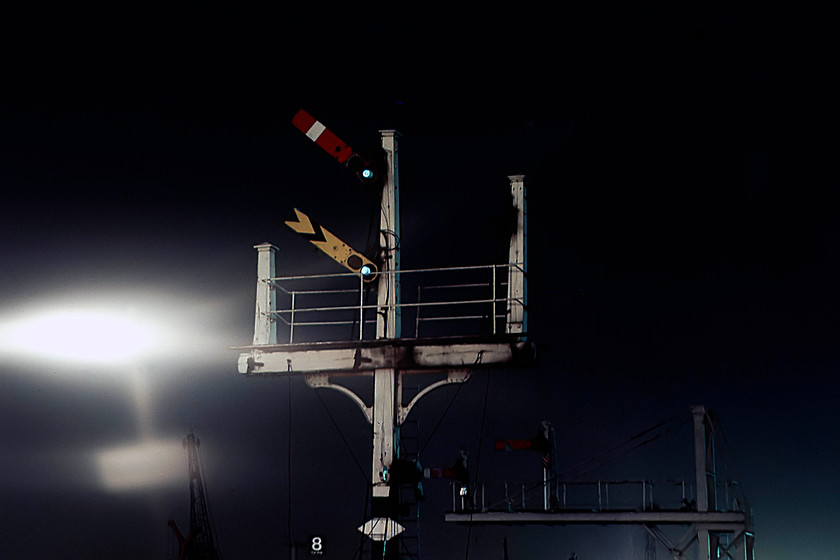 Down fast signal bracket, Cricklewood station 
 An image taken from the northern end of Cricklewood station that shows the down fast home and distant signals pulled off clearing a train to pass. It is a wooden Midland signal with three dols but only one remains in use. Notice the strange ghosting effect with a lighting post and running in sign seen to the left of the photograph. 
 Keywords: Down fast signal bracket Cricklewood station