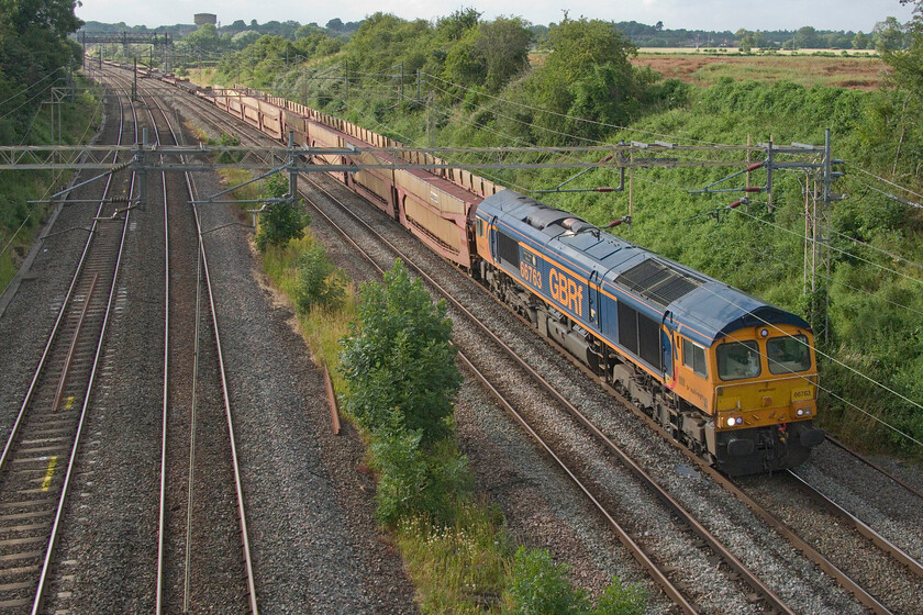 66763, 14.08 Garston-Dagenham Dock Reception (6L48, 5E), Victoria bridge 
 66763 'Severn Valley Railway' passes Victoria bridge between Roade and Ashton leading the 14.08 Garston to Dagenham Docks empty cartic. Limited to sixty mph the 6L48 runs in the afternoon and into the evening presumably to cause less congestion as it makes its way south. Rather like the bottled water train, when empty these wagons make a lot of noise with a very distinctive resonance. Also, I always notice that the staff who unload the cars at Garston leave the large metal wheel chocks used to secure the load strewn about the flatbed wagons (towards the rear of this train). It always strikes me that these could easily vibrate themselves off the side of the wagons and be a potentially serious hazard to other railway users. 
 Keywords: 66763 14.08 Garston-Dagenham Dock Reception 6L48 Victoria bridge cartic Severn Valley Railway