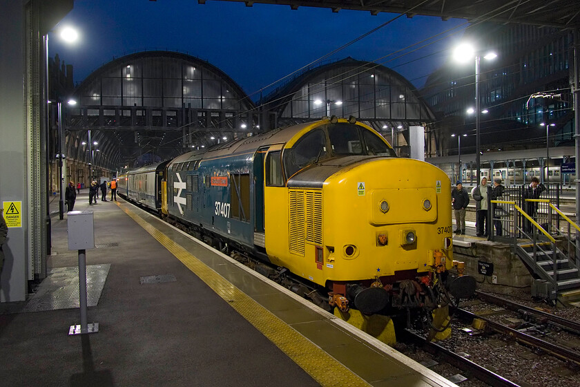 37407, outward leg of the Carols at Norwich Cathedral, 07.22 London King's Cross-Norwich (1Z39, RT), London King's Cross station 
 37407 'Blackpool Tower' stands at the head of the 1Z39 07.22 King's Cross to Norwich (with an optional return run to Great Yarmouth and Lowestoft) prior to departure from London. By now it was nearly 07.30 and the driver had not arrived to start the veteran Type 3 up. It does not look very busy but behind me were probably twenty-five enthusiasts all eager to get their own photographs and witness the departure. 
 Keywords: 37407 Carols at Norwich Cathedral 07.22 London King's Cross-Norwich 1Z39 London King's Cross station Blackpool Tower