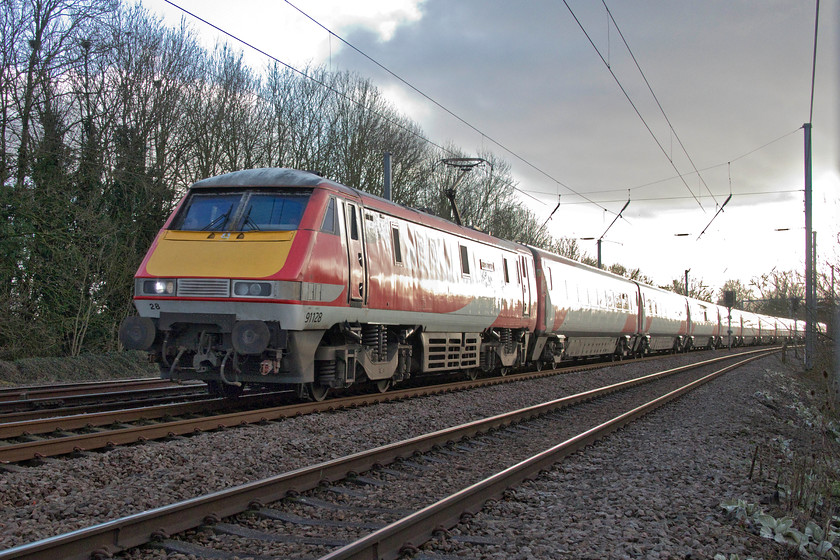 91128, GR 12.35 London King`s Cross-Leeds (1D14, 4L), Gill`s Crossing 
 The 12.25 London King's Cross to Leeds 1D14 has yet to go over to Azuma with it still being formed by a Mk. IV set, on this winter day led by 91128 'InterCity 50'. The train is seen passing Gill's Crossing, a popular walking route in the village of Offord Cluny. Ironically, as it is so popular, I suspect that it is one that will soon be closed as Network Rail continues on its seemingly obsessive mission to close all access points. 91128 was one of the last class 91s to be released into traffic at the start of 1991 meaning it is coming up for thirty years old, I wonder, at the time of writing, if it will celebrate this landmark birthday but in the hands of another operator and on a different route? 
 Keywords: 91128 12.35 London King`s Cross-Leeds 1D14 Gill`s Crossing InterCity 50 LNER