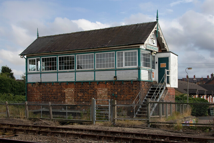 Sleaford West signal box (GN, 1882) 
 Sleaford West signal box has been retained to operate the King Edward Street level crossing on which I am standing to take this photograph of the fine Great Northern box dating from 1882. Apart from replacement UPVC windows that at least have a similar glazing arrangement to the originals, the box looks good complete with its slate roof, wooden panelling and finials. Until the two busy level crossings in Sleaford become automated both East and West boxes will remain in use. There is a photograph taken from a similar spot when I visited Sleaford back in 1980, see....https://www.ontheupfast.com/p/21936chg/29682557204/sleaford-west-signal-box-level-crossing 
 Keywords: Sleaford West signal box