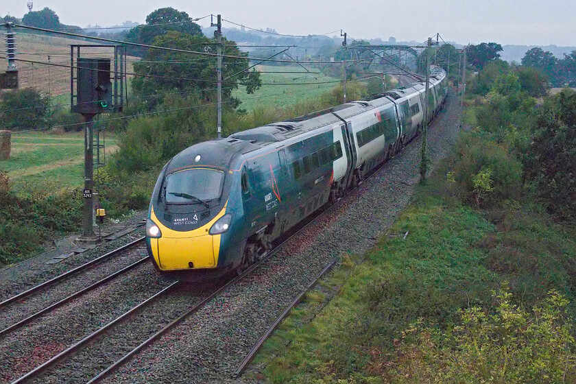 390107, 05.55 Manchester Piccadilly-London Euston (1A07, 3L), Milton crossing 
 In the autumnal half-light at Milton crossing between Roade and Blisworth 390107 heads south working Avanti's 05.55 Manchester to London Euston service. The camera struggled in the half-light but Photoshop came to the rescue to sort out some of the issues. 
 Keywords: 390107 05.55 Manchester Piccadilly-London Euston 1A07 Milton crossing AWC Avanti West Coast