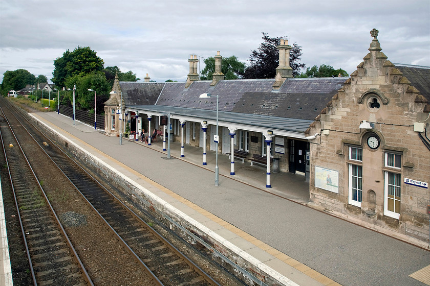 Nairn station 
 A station was first opened at Nairn by the Inverness and Nairn Railway in 1855 with the station building seen here opening in 1885. According to Historic Environment Scotland, the station is a ''long single-storey H-plan building on the down platform with low wing to east. Coursed rubble with broached ashlar dressings. Projecting cross-wings with crowstepped gables and carved stone finials, rose, thistle and star; west gable end to platform with canted bay window. Platform canopy borne on clustered cast-iron columns on hexagonal bases. Tall square and round chimney stacks; slate roof.'' All I know is that they sold a smashing cup of coffee at the small caf seen on the platform! 
 Keywords: Nairn station Inverness and Nairn Railway