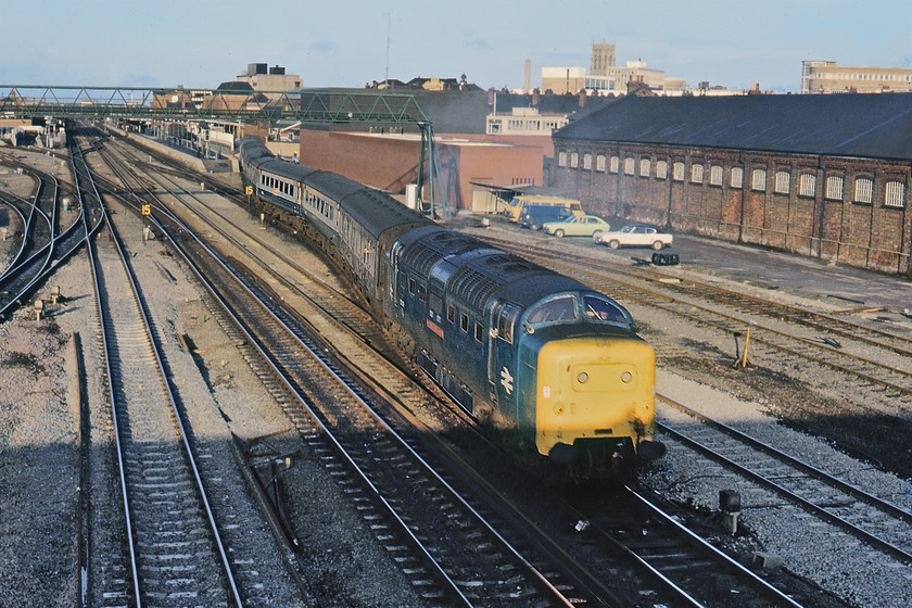 55016, 12.34 Hull-London King's Cross (1A18), Doncaster St. James' bridge 
 Having seen 55016 'Gordon Highlander' enter Doncaster station a little earlier Graham and I must have leapt into the Austin 1100 and raced to the south of the station to St. James' bridge to secure a second photograph. With the tower of Doncaster Minster in the background, the station is seen to the top left with just a DMU waiting at a platform. Unfortunately, the low winter sunshine and my ineptitude have meant that the lower nose of the Deltic is in the shade as it weaves away from the station with the 1A18 Hull to King's Cross. Notice the Mk. I Ford Capri complete with a vinyl roof parked in the background next to a green Vauxhall Chevette and some BR Dodge Spacevans (formally Comma vans). 
 Keywords: 55016 12.34 Hull-London King's Cross 1A18 Doncaster St. James' Bridge Gordon Highlander