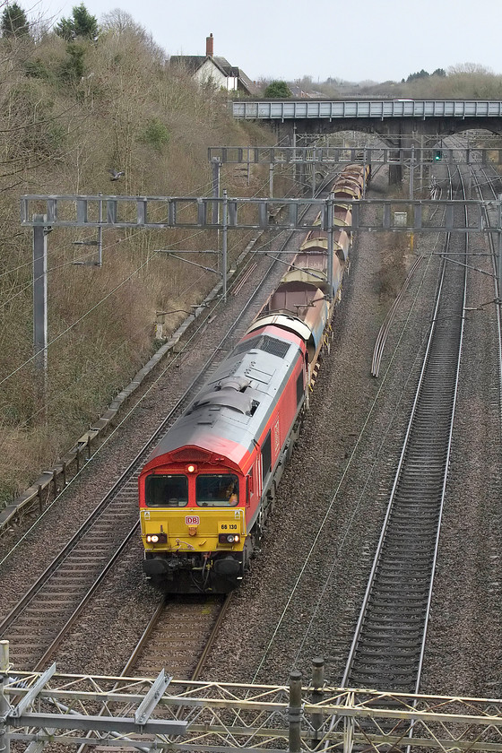 66130, 11.00 Tring-Bescot, Hyde Road bridge, Roade 
 66130 leads the 11.00 Tring to Bescot engineers' train through Roade about to pass under Hyde Road bridge. I was pleased to get a shot of this 66 as it was a photographic cop! Notice the building on the skyline with the very tall chimney stack, this was the former station master's house with Roade station being just beyond the A508 bridge. 
 Keywords: 66130 11.00 Tring-Bescot Hyde Road bridge Roade