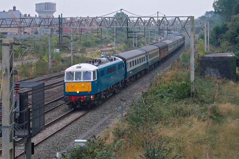 86259, outward leg of The Cumbrian Mountain Express, 06.39 London Euston-Carlise (1Z86, 6L), site of Roade station 
 As usual, running on the down fast line, 86259 'Les Ross/Peter Pan' passes Roade a little late leading the 06.39 Euston to Carlisle Cumbrian Moutain Express. Often, if this regular charter is late signallers will path it on the down slow as far as Hanslope Junction where it will be held until a reasonable path between AWC services is found. Today, running some ten minutes late here at Roade this did not happen with a number of Pendolinos now two signals behind it and running on double caution all the way to Rugby. Good running was maintained for the rest of the journey to Carlisle from here including the steam-led section with SR 34067 'Tangmere' putting in a good performance over Shap. However, things went badly wrong on the return journey with Tangmere failing in spectacular fashion just south of Appleby. Eventually, 47812 was able to take the train back to Carlisle where it also promptly failed resulting in 86259 'Les Ross/Peter Pan' being summoned from Carnforth. The AL6 then took the train back to Euston arriving, I believe, after midnight, what a shame for all concerned. 
 Keywords: 86259 The Cumbrian Mountain Express, 06.39 London Euston-Carlise 1Z86 site of Roade station Les Ross Peter Pan