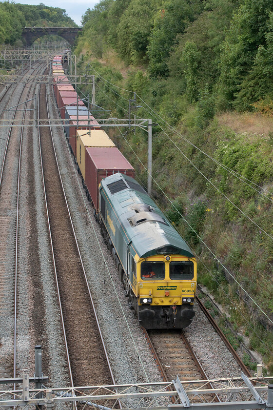 66593, 12.16 Lawley Street-London Gateway (4L46, 4E), Hyde Road bridge 
 66593 makes sedentary progress through Roade cutting taken from Hyde Road bridge leading the 12.16 Lawley Street to London Gateway Freightliner. When at the DRS open day a week previously Mike and I spoke with a driver on a number of issues. One thing that he confirmed was that a heavily loaded train heading south from Northampton towards Roade can be quite a battle for a Class 66, especially when it is held at the station necessitating a standing start prior to making the climb. 
 Keywords: 66593 12.16 Lawley Street-London Gateway 4L46 Hyde Road bridge Freightliner