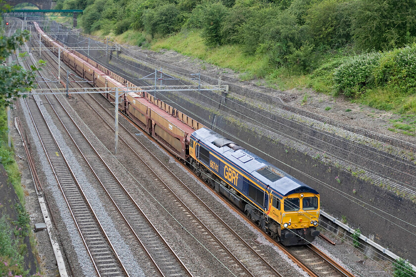 66741, 14.33 Garston-Dagenham (6L48), Roade cutting 
 GBRf's 66741 brings the 14.33 Garston to Dagenham empty car transporters through Roade cutting. This is a particularly noisy train when empty with a lot of resonance from the huge steel plates that make up the deck and the side panels. When loaded, the vehicles' weight dampens the sound but then the leading locomotive is making a lot more noise of course! 
 Keywords: 66741, 14.33 Garston-Dagenham 6L48 Roade cutting GBRf