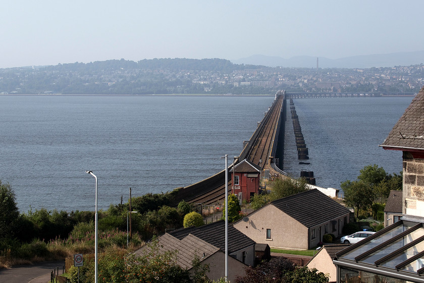 Tay Bridge & Tay Bridge South signal box (NB, 1897) from Stewert Road, Wormit 
 This elevated view of the Tay Bridge is taken from a driveway entrance in the village of Wormit, unfortunately, no train was due and we had to get on to our evening destination so this shot had to suffice. Notice the piers from the former bridge that collapsed in a storm on the night of 28th December 1879 killing seventy-nine passengers and crew who were in a train that plunged into the waters of the Tay. An interesting feature, that I did not spot until processing the picture, is the lines in the water at right angles to the bridge to the left. I suspect there was an incoming tide and that these lines are caused by the piers of the bridge. 
 Keywords: Tay Bridge Tay Bridge South signal box Stewert Road, Wormit