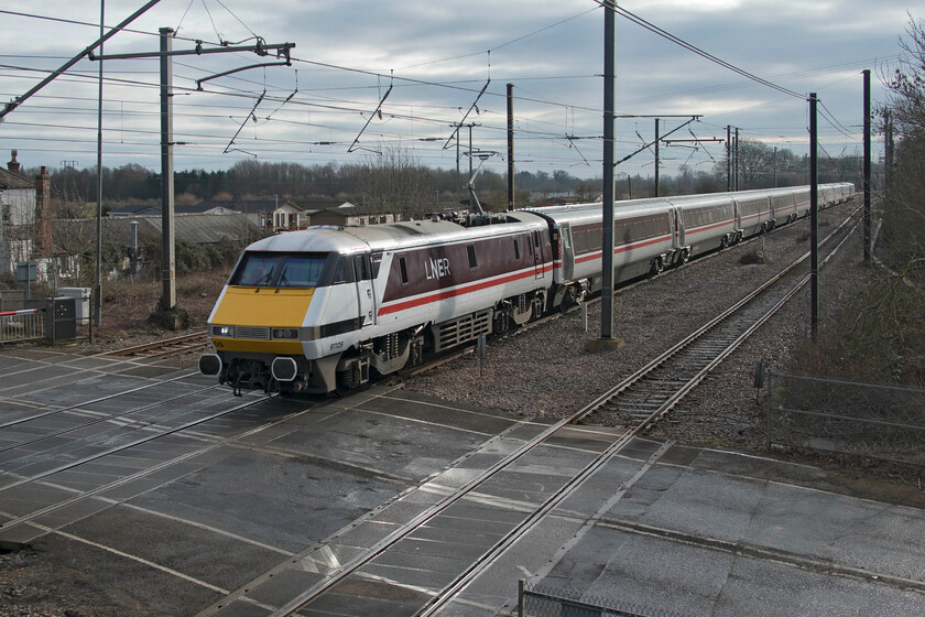 91105, GR 09.06 London King's Cross-York (1N81, 5L), Tallington 
 Catching a little weak morning sunshine the 09.06 King's Cross to York service passes Tallington level crossing taken from the steps of the footbridge. The train is led by 91105 and its matching set of LNER's version of the InterCity Executive livery. 
 Keywords: 91105 09.06 London King's Cross-York 1N81 Tallington LNER IC225 InterCity executive