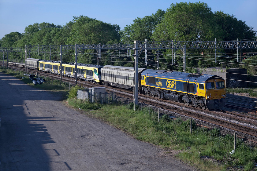 66715 & 777007, 02.44 Dollands Moor-Kirkdale (6X29, 15E), site of Roade station 
 Having arrived on UK soil through the Channel Tunnel two days previously, brand new Stadler built 777007 is taken north to Liverpool being dragged by 66715 'Valour'. Deliveries of Merseyrail's new units, that are replacing their positively ancient BR era Class 507 and 508 units, will be coming thick and fast over the coming months but I suspect that there will be some COVID-19 related delays. Complete with some barrier wagons front and rear, the 02.44 Dollands Moor to Kirkdale running as 6X29 is seen passing a sunny Roade. 
 Keywords: 66715 777007 02.44 Dollands Moor-Kirkdale 6X29 site of Roade station Valour Merseyrail Stadler