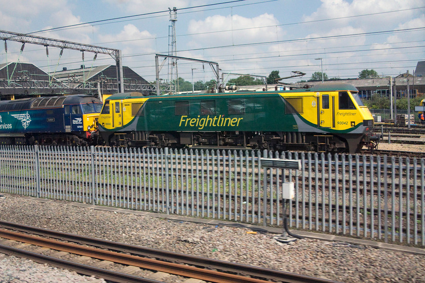 57301 & 90042, stabled, Willesden MPD 
 57301 'Goliath' and 90042 ars both seen as our train speeds past Willesden MPD in the final approach to Euston. The two liveries of these engines is somewhat different. The brash and very bright Freightliner paintwork contrasts with the much more subtle and perhaps classy DRS livery. 
 Keywords: 57301 90042 Willesden MPD