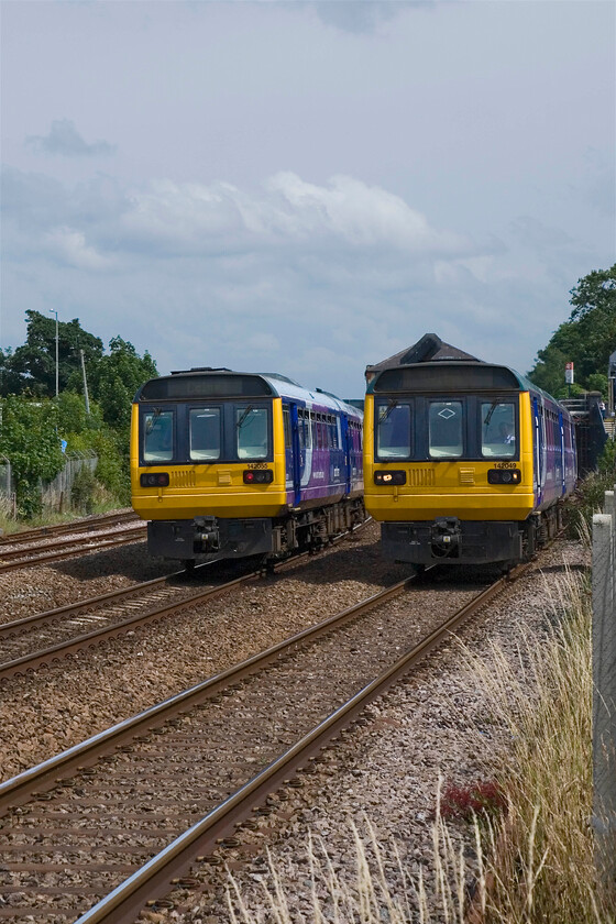 142055, NT 13.44 Blackpool South-Colne & 142049, 12.50 Colne-Blackpool South, Kirkham SD418327 
 A pair of Pacers pass just west of Kirkham and Wesham station the roof of which can just be seen. To the left Northern's 13.44 Blackpool South to Colne is being worked by 142055 whilst 142049 works the 12.50 Colne to Blackpool South. I was pleased that I made the decision to pop my trusty steps in Andy's car before we left yesterday as without them this photograph (and the previous one for that matter) would have been impossible because of the tall fence just visible to the extreme right of the shot. 
 Keywords: 142055 13.44 Blackpool South-Colne 142049 12.50 Colne-Blackpool South Kirkham SD418327