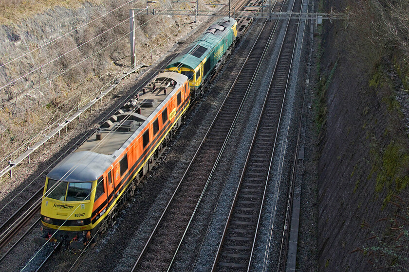 90047 & 66418, 08.01 Felixstowe North-Crewe Basford Hall (4M81, 38L), Roade cutting 
 The 4M81 is a rare visitor to the WCML as it usually takes the Ely, Peterborough and Leicester route. I think that it was re-routed due to the failure of 66418 'Patriot - In Memory of Fallen Railway Employees' seen second in the consist as the timings on RTT showed it languishing at Ipswich for some time. I suspect that the only locomotive available to take the train forward was 90047 hence it having to be re-routed under the wires. The 08.01 Felixstowe to Crewe Basford Hall Freightliner only arrived some forty minutes adrift so things did not end up as bad as they may have done! 
 Keywords: 90047 66418 08.01 Felixstowe North-Crewe Basford Hall 4M81 Roade cutting Freightliner Patriot-In Memory of Fallen Railway Employees