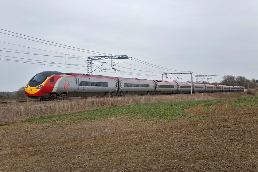 390130, VT 17.17 London Euston-Liverpool Lime Street, Milton crossing 
 Having seen (briefly through the trees) and heard the familiar sound of a Class 47 hauling a returning footex (the purpose of my late afternoon trip out) in the distance taking the Northampton line thus avoiding my chosen spot I headed for home. As I did so I turned my camera one last time to photograph Virgin's 390130 passing between Roade and Blisworth with the 17.17 Euston to Liverpool service. I can console myself with the fact that the weather is poor with very 'flat' and grey conditions. 
 Keywords: 390130 17.17 London Euston-Liverpool Lime Street Milton crossing Virgin West Coast Pendolino