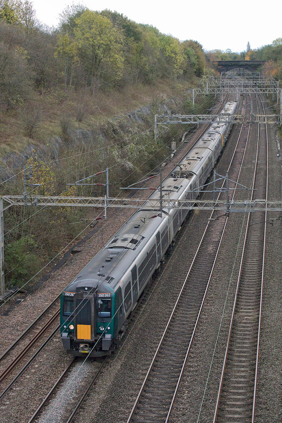 350262 & 350112, LN 11.55 London Euston-Northampton (2Z27, 7E), Roade cutting 
 I think that the livery applied to some of the class 350s, as seen here in Roade cutting, looks ridiculous! The silly yellow square and dark green paintwork is reminiscent of the British Railways green livery applied to much of its diesel fleet in the early 1960s, it didn't look good then and it's the same now! 350262 and 350112 form the 11.55 London Euston to Northampton, an unusual service with the headcode 2Z27. On studying Realtime Trains it was clear that a London Northwestern temporary timetable was in place with all trains going as far as Northampton and then heading back south from there. Trains were re-timed and most assigned with 2ZXX headcodes. On logging on to their website they stated that 'due to a temporary shortage of traincrew over half term (including those volunteering for overtime), we will be running an amended timetable south of Rugby on Saturday.' This ended a disastrous week for the company with delays every day causing hours of disruption for its passengers, see.... https://www.bbc.co.uk/news/uk-england-50262788 
 Keywords: 350262 350112 11.55 London Euston-Northampton 2Z27 Roade cutting