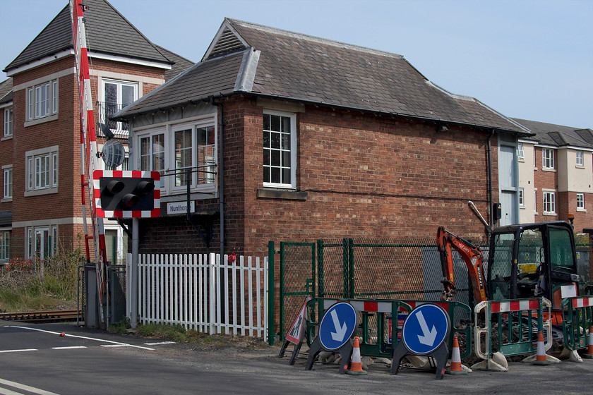 Nunthorpe signal box (NE, 1903) 
 The rear view of Nunthorpe signal box taken from the level crossing. The box is grade II listed so this accounts for its survival in its current form. For example, the windows were replaced in 2011 but they replicate the original timber ones having an identical glazing pattern and the balcony also survives. In addition, no toilet block has been added that is an all too often occurrence but the recent green security fencing spoils the scene. A particularly notable feature is the gablet mounted ventilators that cleverly combines the constructional advantages of a gabled and a hipped roofed, producing a visually striking signal box. 
 Keywords: Nunthorpe signal box