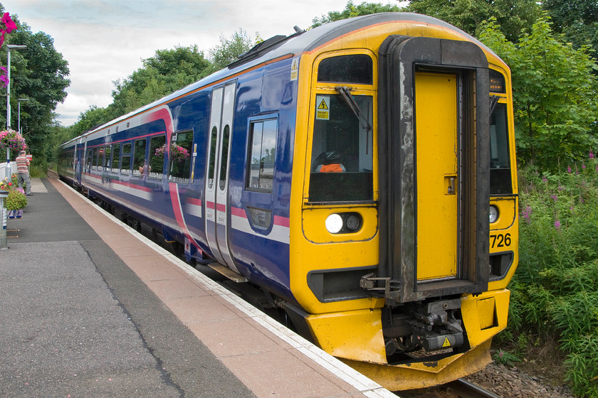 158726, SR 12.34 Wick-Inverness (2H62), Alness station 
 The town of Alness has a proud history of entering and winning the Scotland and Britain in Bloom competitions with this extended to the railway station that was adorned with numerous hanging baskets, boxes and manicured grass off the platform end. ScotRail's 158726 arrives at the station with the 12.34 Wick to Inverness service. 
 Keywords: 158726 12.34 Wick-Inverness 2H62 Alness station ScotRail