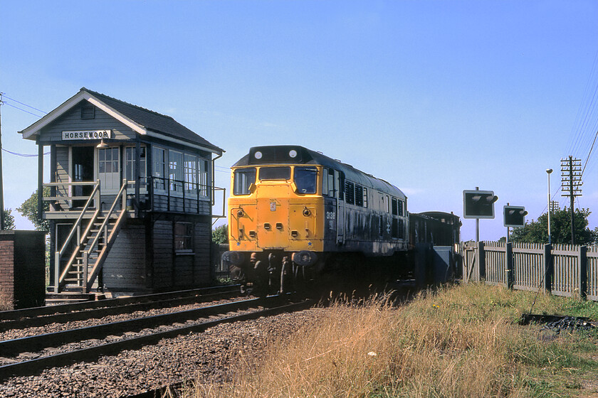 31318, up freight, Horsemoor 
 Having visited Horesmoor yesterday we returned today to find the gates down and a train pegged. My notes state that we were the wrong side of the line with no time hence the shadows and the rather rushed composition of this photograph! However, some forty years later I dont care as it contains so much of interest as a reminder of what the railways used to be like. 31289 leads a ridiculously short unfitted freight with the requisite brake van on the rear past the 1899 Great Eastern signal box located just south of March. 
 Keywords: 31318, up freight, Horsemoor.