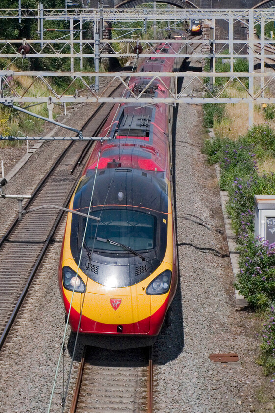 Class 390, VT 10.35 Manchester Piccadilly-London Euston, site of Roade station 
 Poking my camera over the raised parapet of, what is known locally as Gravel bridge in Roade, sees an unidentified Class 390 speeding south working the 10.35 Manchester Piccadilly to Euston service. I was glad to get away from some serious home decorating on such a lovely summer's day, far too nice to be inside! 
 Keywords: Class 390 10.35 Manchester Piccadilly-London Euston site of Roade station Virgin West Coast Pendolino