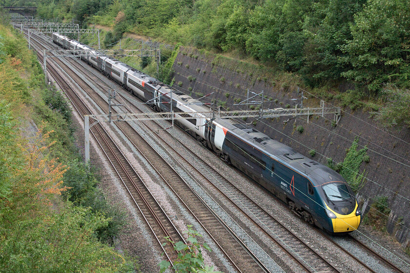 390001, VT 09.51 London Euston-Rugby (5G04, 4L), Roade cutting 
 Pioneer Pendolino 390001 is always recognisable from the front thanks to its gold heart located just below the windscreen. This was applied back in the summer of 2018 when the set was named 'Bee Together' at the start of the city-wide public art experience. It is seen running empty as the 5G04 09.51 Euston to Rugby, the first train to traverse the Weedon loop following an overnight possession. 
 Keywords: 390001 09.51 London Euston-Rugby 5G04 Roade cutting Bee Together