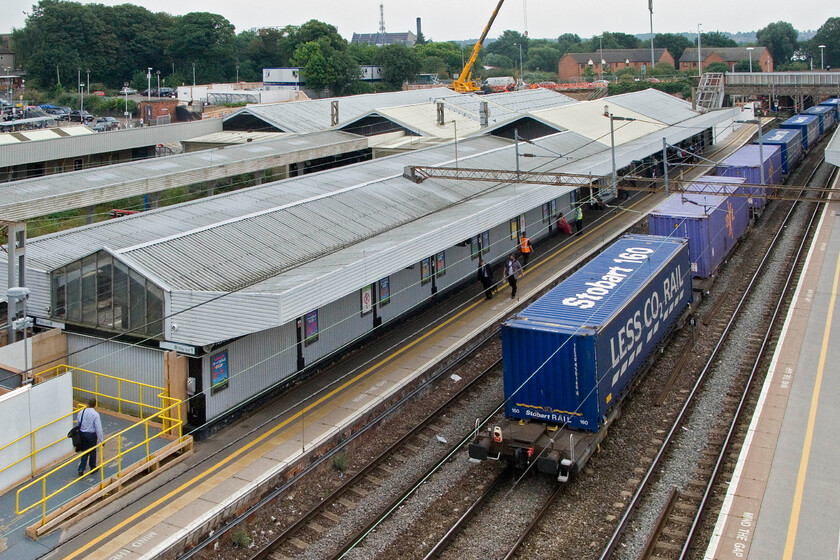 11.15 DIRFT-Tilbury FLT (4L48), Northampton station (from temporary footbridge) 
 The 4L48 11.15 Daventry (DIRFT) to Tilbury FLT (Tesco Express) makes its way slowly away from Northampton station after being held for a London-bound unit has departed. This new vantage pint from the station's rather rickety and open station footbridge gives a commanding view of the old station whist the new one begins to take shape in the background where the crane is at work. 
 Keywords: 11.15 DIRFT-Tilbury FLT 4L48 Northampton station from temporary footbridge