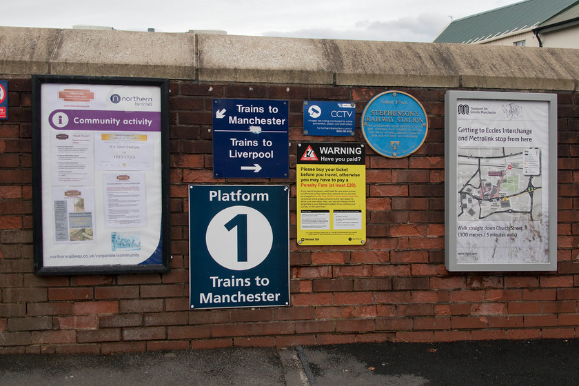 Notices, Eccles station 
 If ever there was a case of too many notices, this has to be it! The cluttered parapet wall by the steps that go down on to Eccles up platform is adorned with a variety of notices ignored by most people I should imagine. Freccles (Freinds of Eccles station) have a large notice to the left. They appear to have been doing excellent work promoting the station and campaigning for a better service. They have also done a superb job keeping the station looking smart with well maintained and stocked flower beds. The blue plaque commemorates that the station is one of Stephenson's stations on his fabled Chat Moss line where it all started in September 1830. 
 Keywords: Notices Eccles station