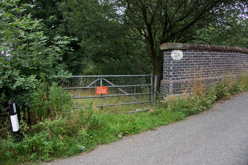 Manor Road bridge, former entrance to Madeley Road station SJ776422 
 Taken from Manor Road that links Madeley with the A53 road is the access to the former Madeley Road station (closed 20.07.1931). Despite no trains having run on the lines that remain deep in the completely overgrown cutting for over twenty years signage and padlocked gates remain the order of the day! The line that once linked the Potteries with Market Drayton (for connections to the Nantwich & Market Drayton and GWR Railways beyond) is truncated a short distance behind me was last in use to carry coal from Silverdale colliery but it is still officially connected to the WCML. 
 Keywords: Manor Road bridge former entrance to Madeley Road station SJ776422