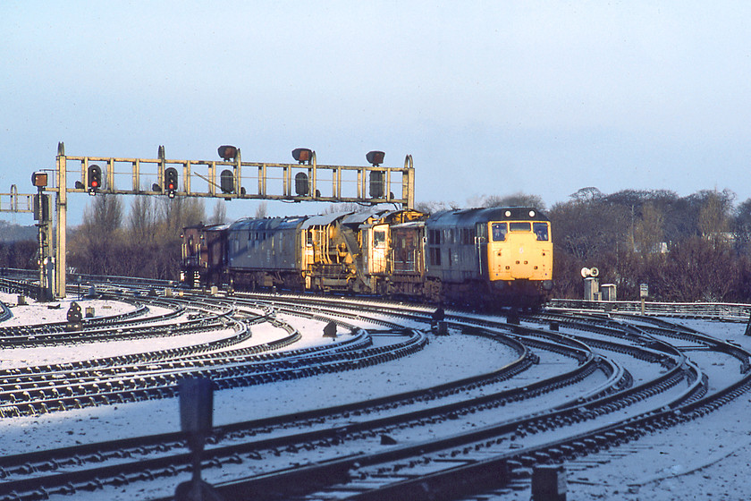 31308, up engineers' train, York station 
 This was the first daylight working observed on Sunday morning taken just after the sun had risen. 31308 approaches York station from the north with an up engineers' train heading off for trackwork somewhere south or west from York. Note the two brake vans positioned front and rear of the consist along with some sort of ballasting machine and what I can only assume was a staff welfare coach of some type. Also note the convoluted track layout to the north end of York station in marked contrast to how it looks today, see..... https://www.ontheupfast.com/p/21936chg/30013256077/x25-180105-gc-15-18-sunderland-london Graham and I were extremely pleased to see the dawn and feel a little warmth on our backs after such a bitter night, off to find some breakfast now! 
 Keywords: 31308 up engineers' train York station