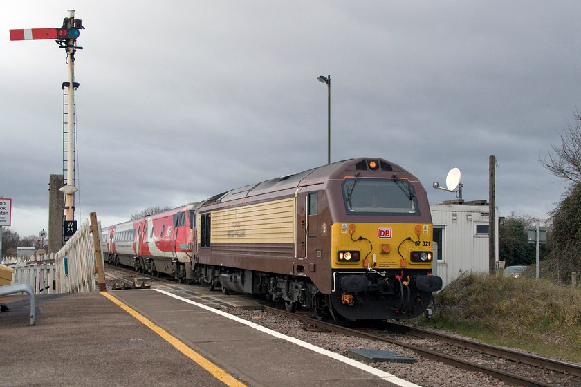 67021 & 82203, GN, 08.43 Leeds-London Kings Cross (1A18, RT), Whittlesea station 
 67021 looks resplendent in its Belmond British Pullman livery as it tows the 08.43 Leeds to London King's Cross through Whittlesea just east of Peterborough. As it's an up service, the DVT is attached to the locomotive; in this particular case, it's 82203. Whittlesea's down home signal can be seen protecting the level crossing over which the train is crossing. Notice the arm's jaunty angle. This is not me having taken the picture at an angle but was how it was. In fact, the signal had to pulled off a couple of times before it satisfied the equipment in the signal box. I think that the S&T team need to visit and do some maintenance! 
 Keywords: 67021 82203 08.43 Leeds-London Kings Cross 1A18 Whittlesea station